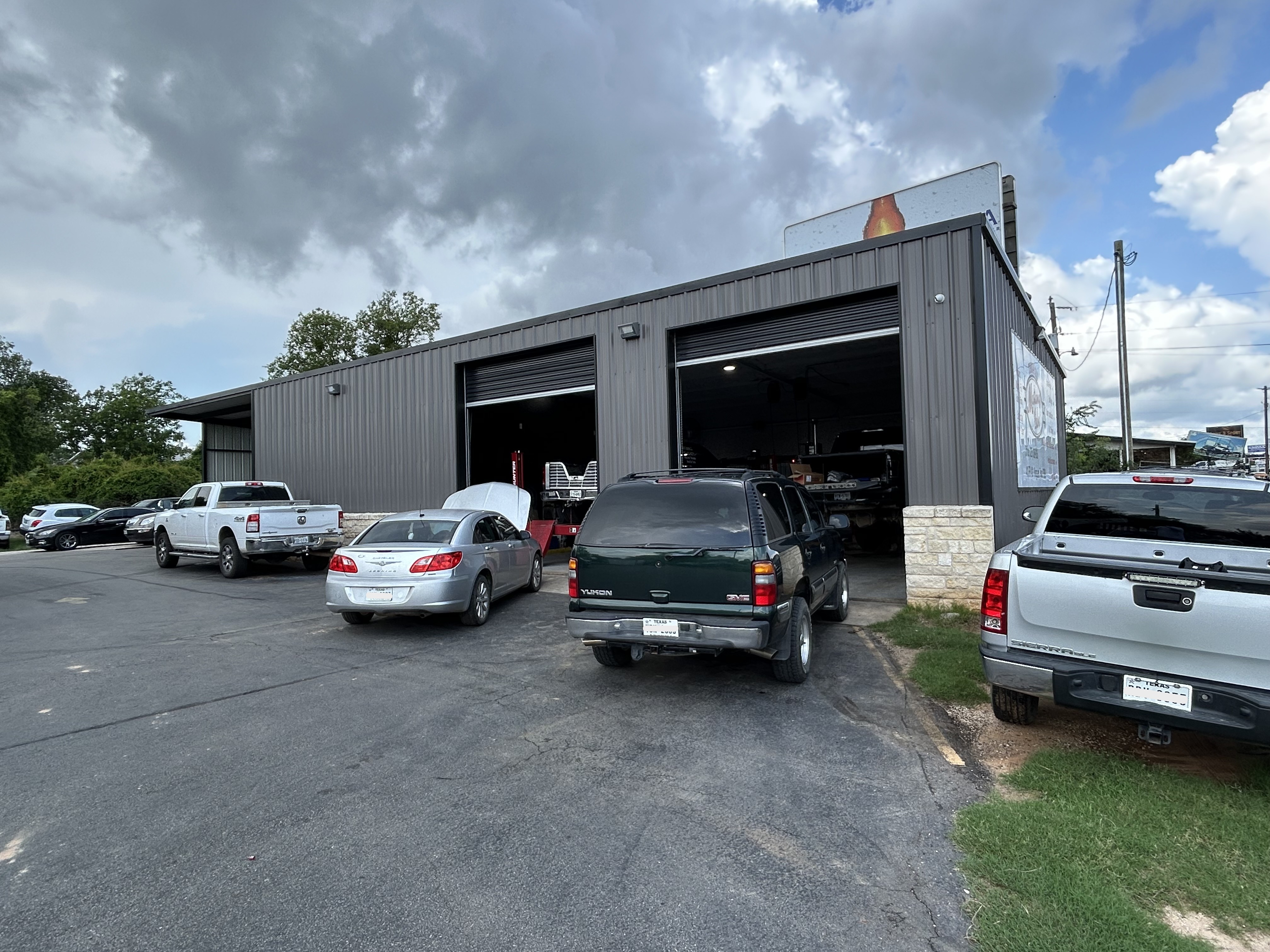 Exterior of Thomas' Mustang Lube & Auto Repair shop on RR Hwy 1431 in Kingsland, TX, with service bays open and customer vehicles parked outside