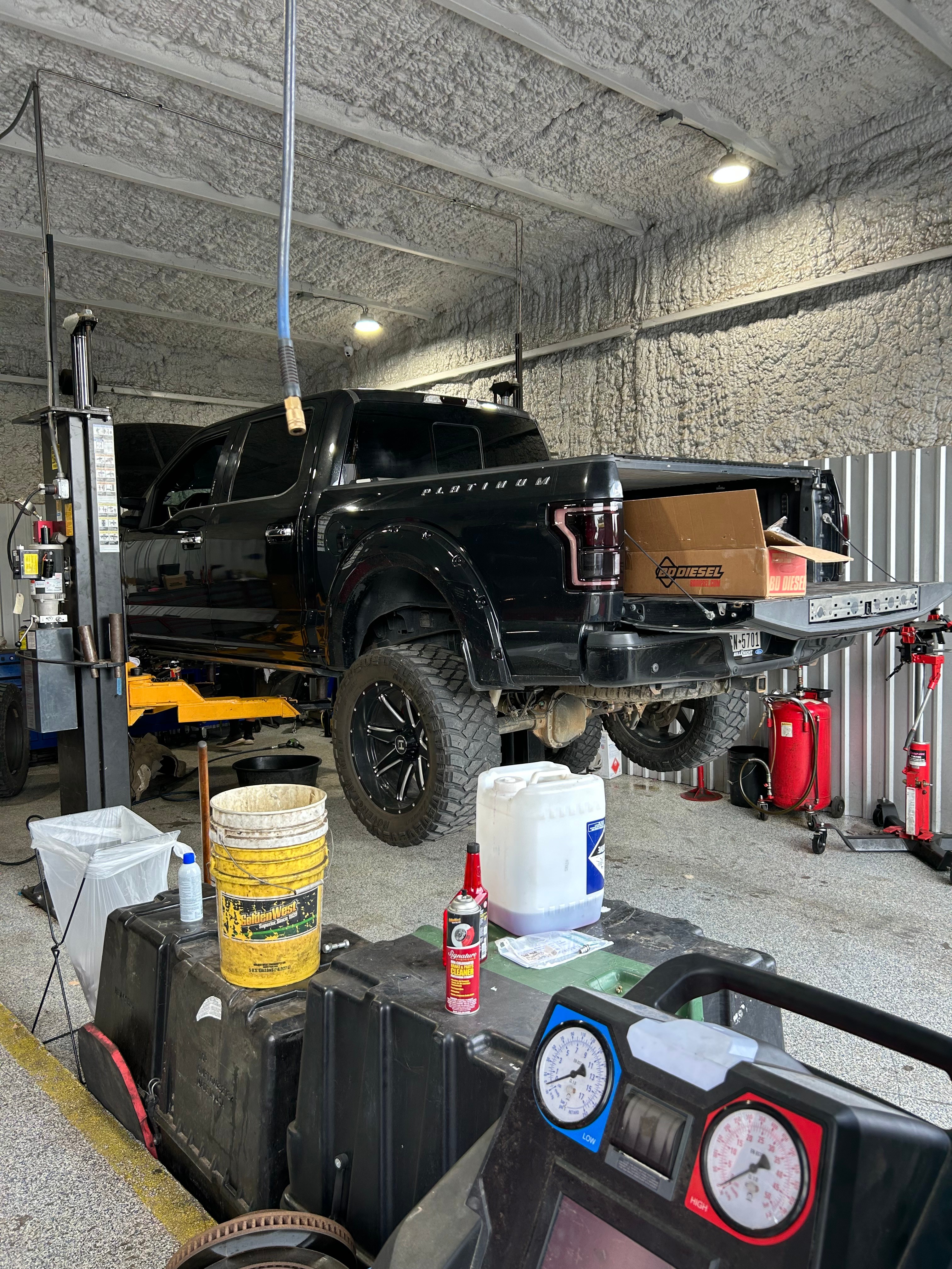 Ford F-150 raised on a lift for undercarriage and suspension work at Thomas' Mustang Lube & Auto Repair in Kingsland, TX